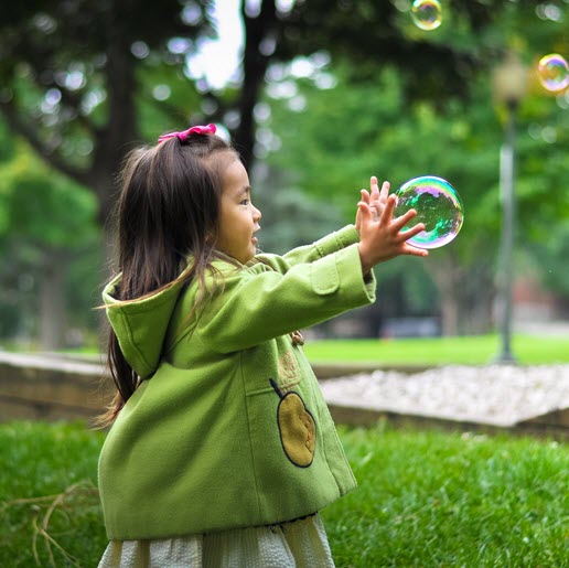 Image of young girl chasing a bubble  from The Compounding Lab in Dayton, Ohio website.